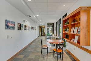 Dining room with baseboards, recessed lighting, a drop ceiling, and dark stone finish flooring