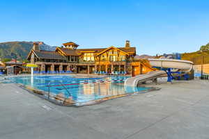 Community pool featuring a water slide, a mountain view, and a patio area