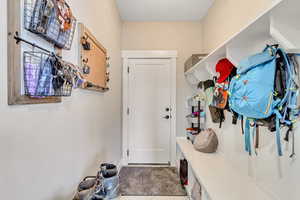 Mudroom with bench and hooks for coats and gear, door goes to the 3 car garage.