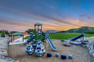 Playground at dusk featuring a mountain view and a gazebo