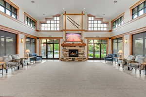 Great  room featuring high vaulted ceiling, healthy amount of natural light, a stone fireplace, and carpet