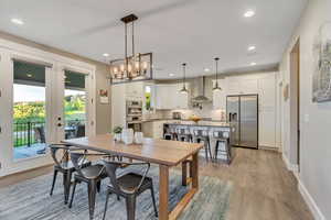 Dining room with light wood-type flooring, recessed lighting,  a chandelier, and french doors