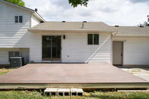 Rear view of house with cooling unit, a deck, and roof with shingles