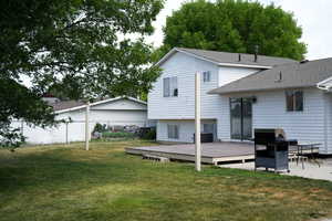 Rear view of house with a wooden deck, roof with shingles, and cooling unit