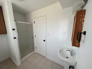 Full bathroom featuring tile patterned floors, baseboards, and a stall shower