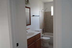 Bathroom with toilet, vanity,  shower combination, and tile patterned flooring