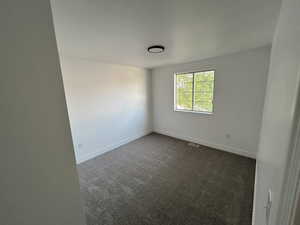 Empty room with dark colored carpet and baseboards