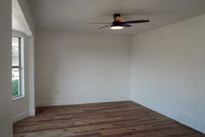 Spare room featuring a ceiling fan, dark wood finished floors, and baseboards