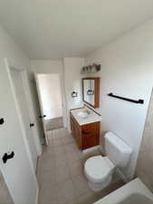 Full bathroom with toilet, vanity, and tile patterned floors
