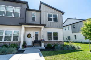 View of front of home with stone siding, board and batten siding, and a front yard