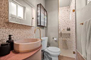 Bathroom with a shower stall, toilet, and vanity