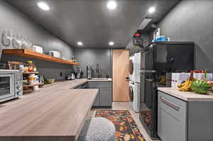 Kitchen with stacked washer / drying machine, a sink, open shelves, recessed lighting, and gray cabinets