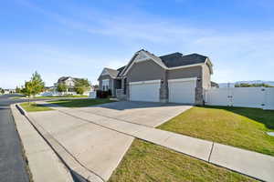 View of front of house with a gate, a garage, stone siding, driveway, and stucco siding