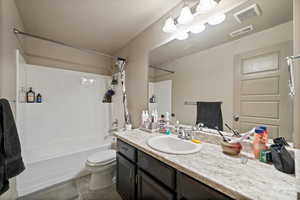 Full bath with shower / tub combo with curtain, toilet, and vanity