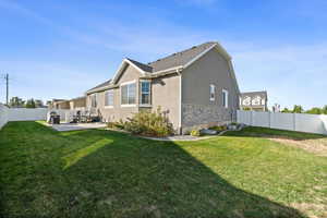 Back of house with stucco siding, a patio, and stone siding