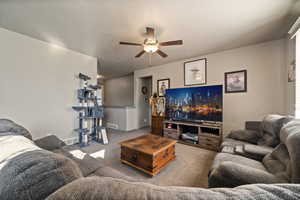 Carpeted living room with ceiling fan and baseboards