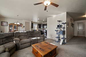 Living area with carpet, a ceiling fan, baseboards, a chandelier, and recessed lighting