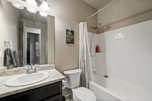 Bathroom with vanity, shower / bath combo with shower curtain, and toilet