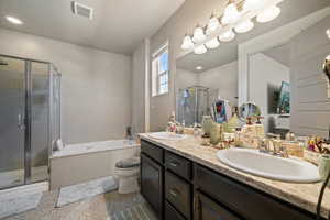 Full bathroom with double vanity, a garden tub, a shower stall, and toilet