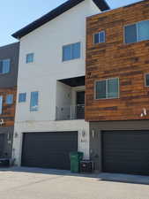 Rear view of house featuring a garage, stucco siding, and cooling unit
