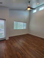 Empty room featuring a ceiling fan, dark wood-style flooring, and baseboards