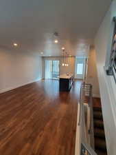 Unfurnished living room featuring a sink, dark wood-style floors, baseboards, and recessed lighting