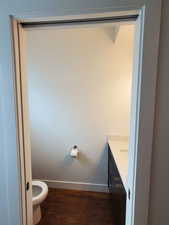 Bathroom featuring vanity, baseboards, toilet, and wood finished floors