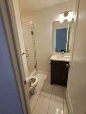 Full bathroom featuring toilet, tile patterned floors, a shower stall, vanity, and baseboards