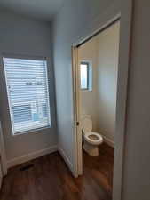 Bathroom featuring wood finished floors, toilet, and baseboards