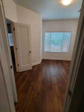Hall with dark wood-style floors and baseboards