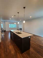 Kitchen with a sink, open floor plan, dishwasher, dark wood-style floors, and an island with sink