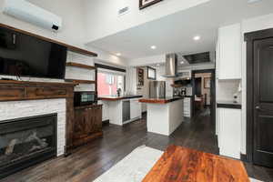 Kitchen with a wall mounted AC, stainless steel appliances, white cabinetry, and a kitchen island