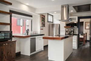Kitchen featuring open shelves, island exhaust hood, appliances with stainless steel finishes, wood counters, and recessed lighting