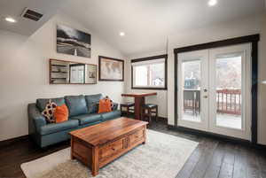 Living area with french doors, hardwood / wood-style floors, lofted ceiling, recessed lighting, and baseboards