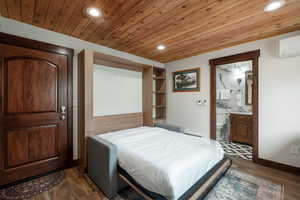 Bedroom with recessed lighting, a wall mounted AC, dark wood-type flooring, wooden ceiling, and ensuite bath