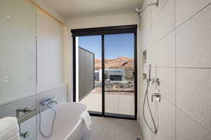 Full bathroom with tile walls, a freestanding tub, and a mountain view