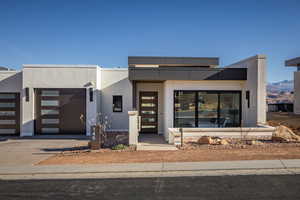 View of front of home featuring concrete driveway, stucco siding, and an attached garage