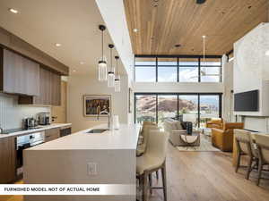 Kitchen with a sink, appliances with stainless steel finishes, modern cabinets, a towering ceiling, and light wood-style floors