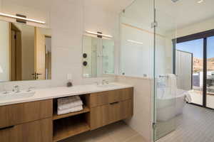 Full bath featuring light tile patterned floors, double vanity, tile walls, a soaking tub, and a stall shower