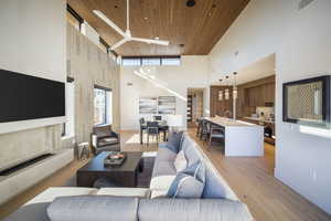 Living area with wood ceiling, a high ceiling, light wood-type flooring, an accent wall, and wooden walls