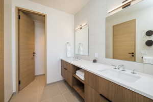 Full bath with double vanity and light tile patterned flooring