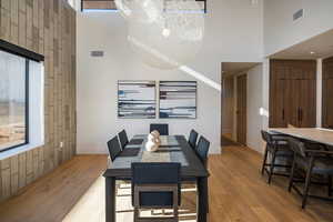 Dining space with light wood finished floors, a high ceiling, and plenty of natural light