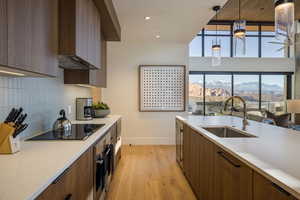 Kitchen with pendant lighting, modern cabinets, brown cabinetry, light wood-style floors, and recessed lighting