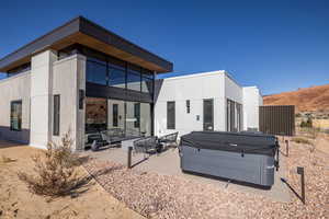 Rear view of house featuring a hot tub, a patio, and outdoor lounge area