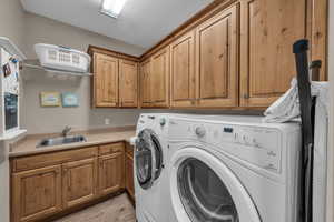 Laundry area featuring washing machine and clothes dryer, cabinet space, and light wood-style flooring