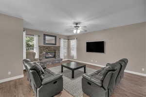 Living area featuring a fireplace, wood finished floors, and ceiling fan