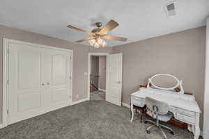 Carpeted home office with a ceiling fan and baseboards