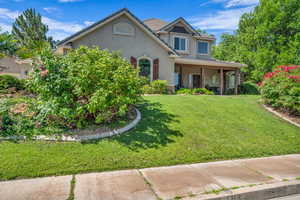 View of front of home featuring stucco siding, a front yard, and covered porch