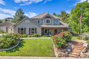 View of front of home with stucco siding, a front lawn, a tile roof, and covered porch