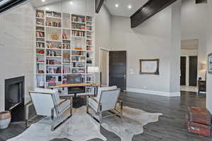 Home office with baseboards, a high ceiling, dark wood-style flooring, recessed lighting, and a fireplace